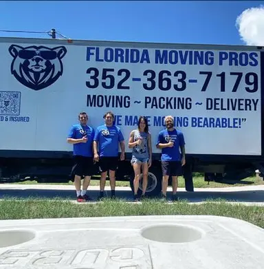 Florida Moving Pros crew posing together in front of a company moving truck on a sunny day