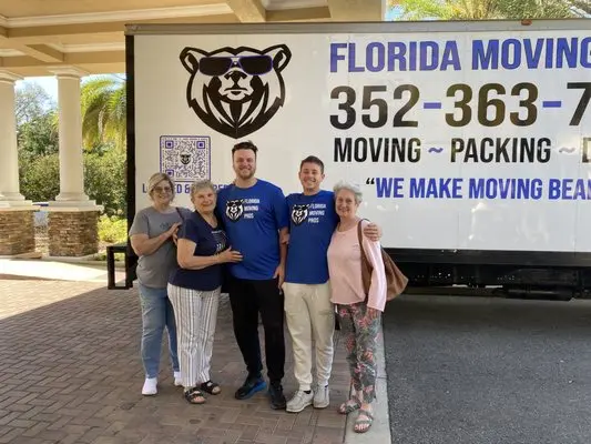Florida Moving Pros team posing with happy customers in front of a moving truck at a residential location