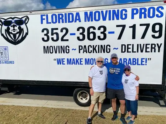 hree movers from Florida Moving Pros standing in front of a branded moving truck outdoors